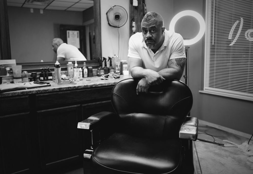 A Grey's barber leaning on his chair inside the shop